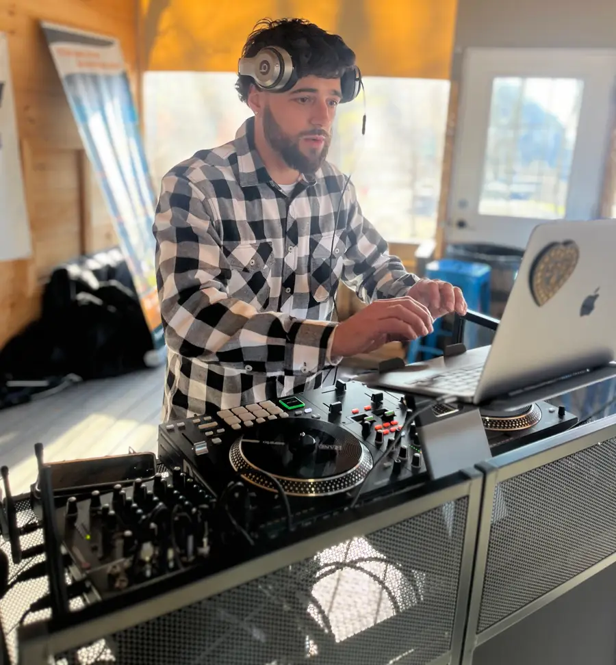 Jon mixing on turntables and a controller, wearing a headset mic